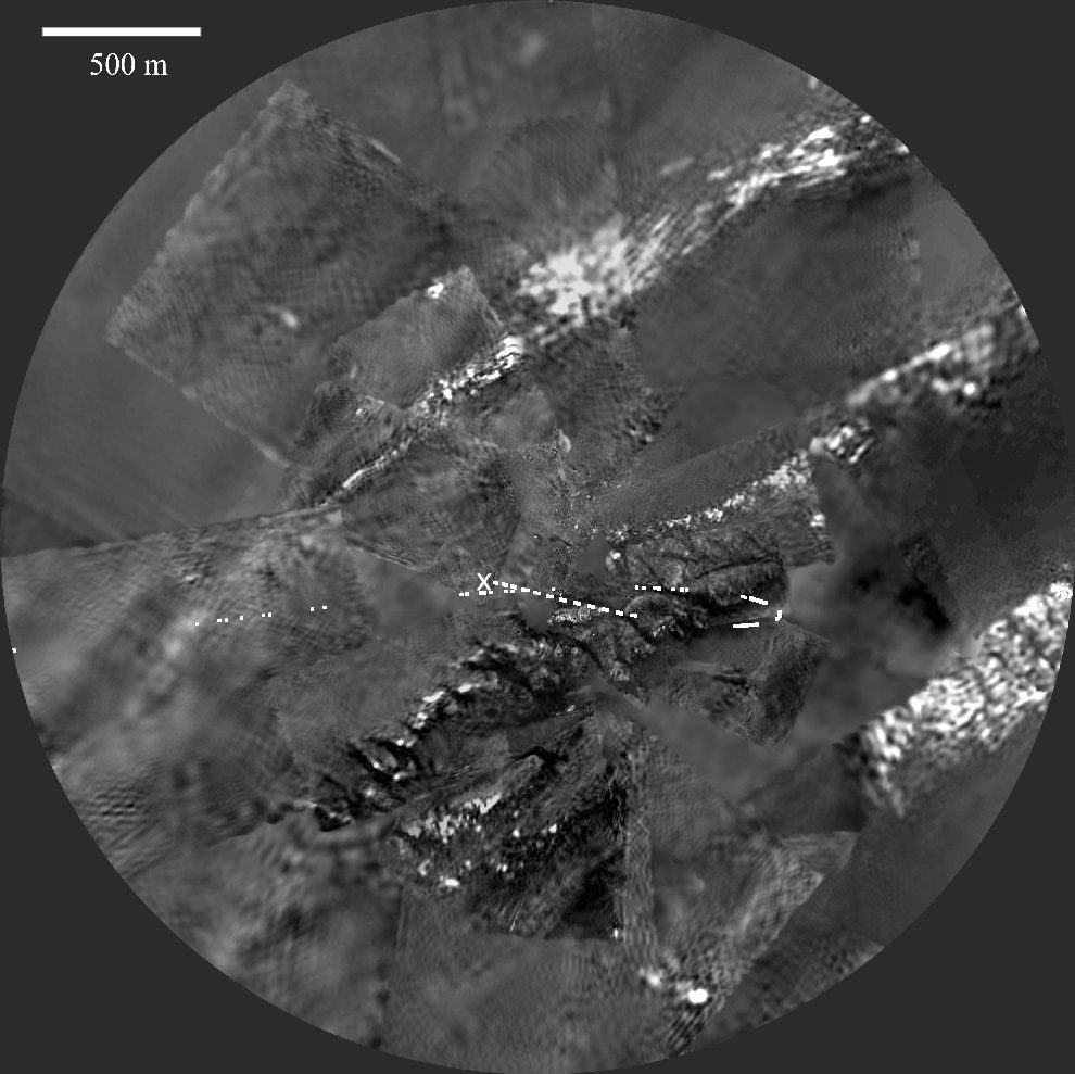 Mosaico circular en blanco y negro del terreno de Titán visto desde el aire, con una zona clara y elevada surcada por redes ramificadas de cauces que desembocan en una llanura oscura.