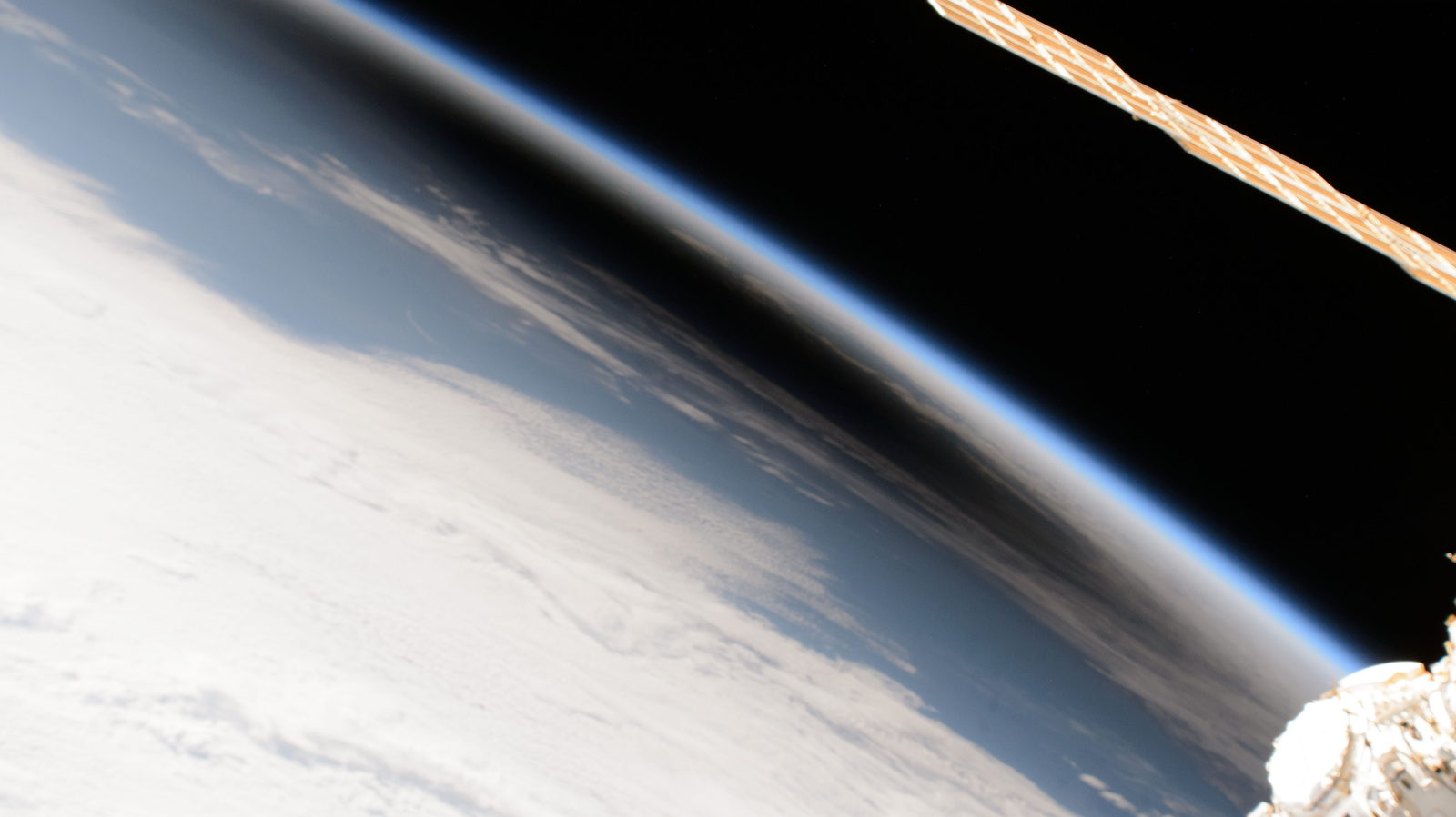 La superficie de la Tierra vista desde órbita con una mancha oscura y difusa, la sombra de la Luna, apoyada sobre las nubes.