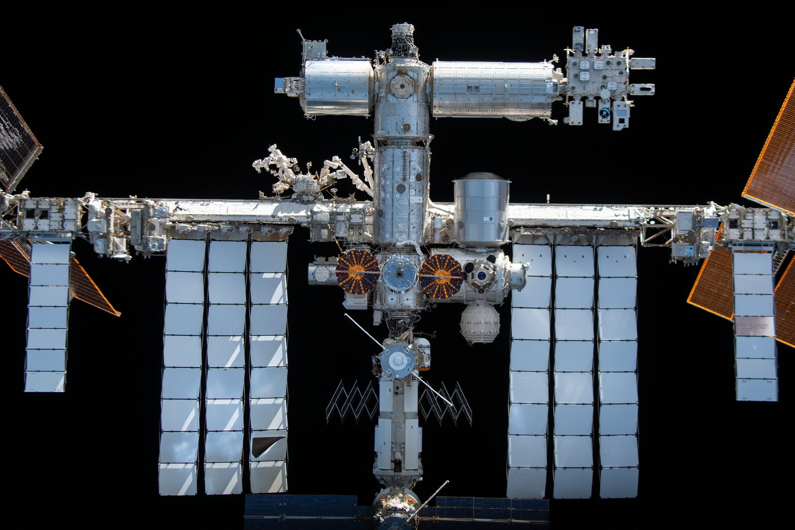 La Estación Espacial Internacional entera, con sus paneles solares dorados desplegados, sobre el azul del océano.